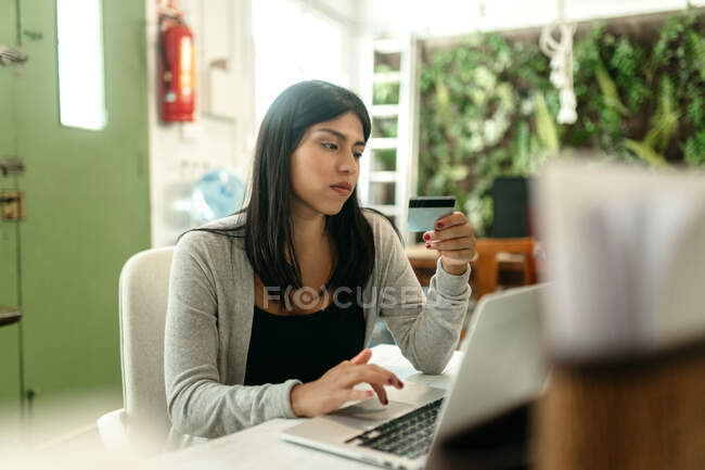 Женщина делает покупки с пластиковой картой для заказа во время онлайн-покупок через ноутбук — стоковое фото