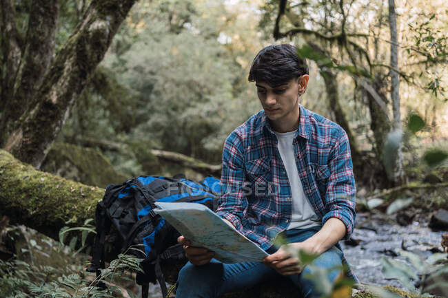 Focused male explorer reading map while searching for trail during trekking trip in jungles — Stock Photo