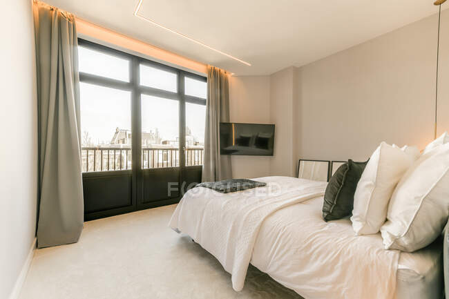 Interior do quarto com cama macia com travesseiros colocados na frente da janela — Fotografia de Stock