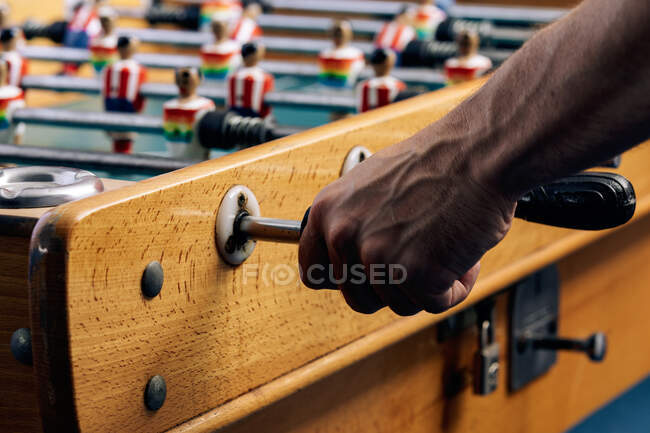Crop unrecognizable African American male playing table soccer game while entertaining at weekend — Stock Photo