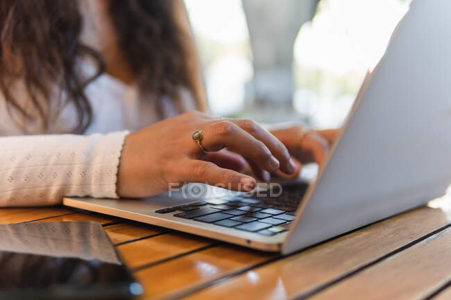 Cortado irreconhecível jovem estudante latino-americano ler informações na tela do laptop enquanto se prepara para o exame universitário no café acolhedor — Fotografia de Stock