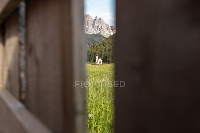 Through opened wooden door of old catholic St John church located in green valley in Dolomite Mountains on sunny day — Stock Photo