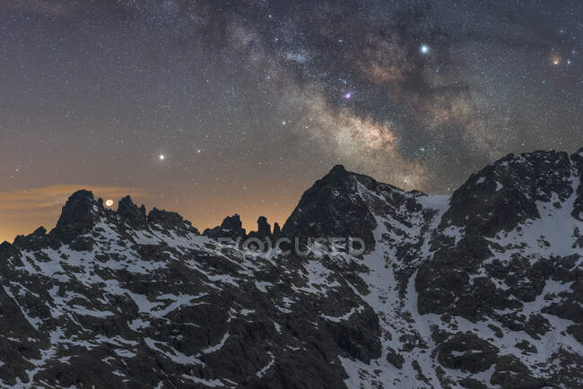 Espectacular vista de la galaxia en el cielo con gas interestelar sobre el monte majestuoso áspero con nieve en la noche - foto de stock