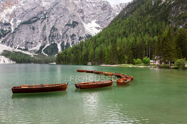 Wooden boats floating on lake Braies on background of Dolomites Mountains on cloudy day — Stock Photo