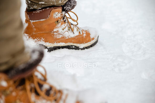 Crop of unrecognizable male walking along snowy road in winter woods — Stock Photo