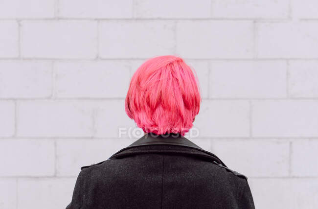 Зворотній перегляд врожаю невизначена жінка з фарбованим волоссям, що стоїть біля білої стіни — стокове фото