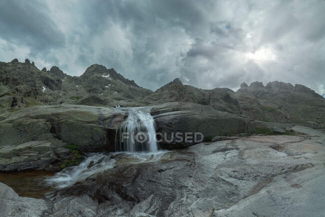 Vue panoramique de la Sierra de Gredos avec cascade et étang sous un ciel nuageux — Photo de stock