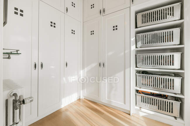 Interno di ampio ripostiglio bianco con armadio a muro e ripiani con contenitori in metallo progettati in stile minimale — Foto stock