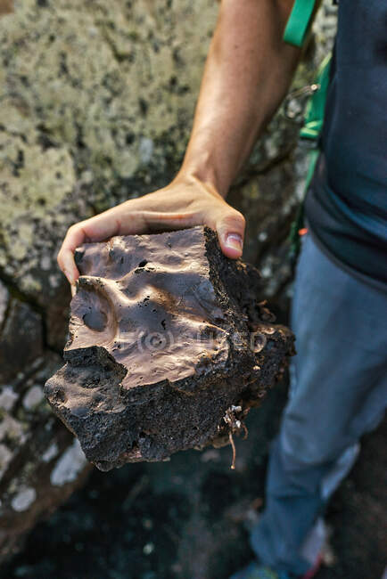 D'en haut homme anonyme démontrant morceau de roche rugueuse tout en explorant la campagne en été — Photo de stock