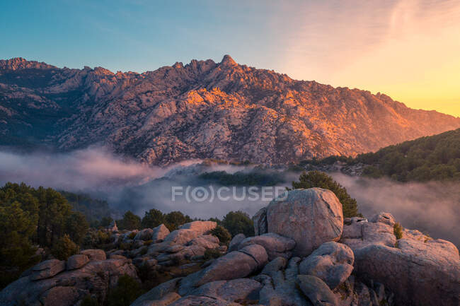 Сценічний вигляд Педрізи з туманом, який дифундує між горами Гвадарама та валунами з хвойними деревами на світанку в Іспанії. — стокове фото
