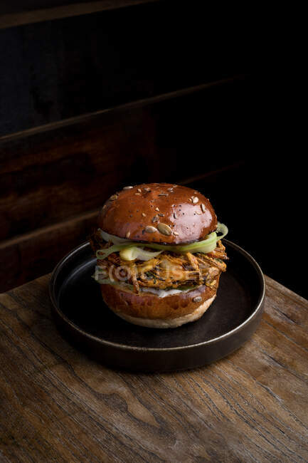 Зверху смачний бургер зі смаженими булочками та овочами, які подаються на тарілці та поміщаються на дерев'яний стіл у ресторані — стокове фото