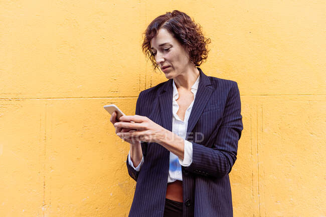 Самозабезпечена елегантна жінка в офіційному вбранні стоїть на екрані мобільного телефону — стокове фото