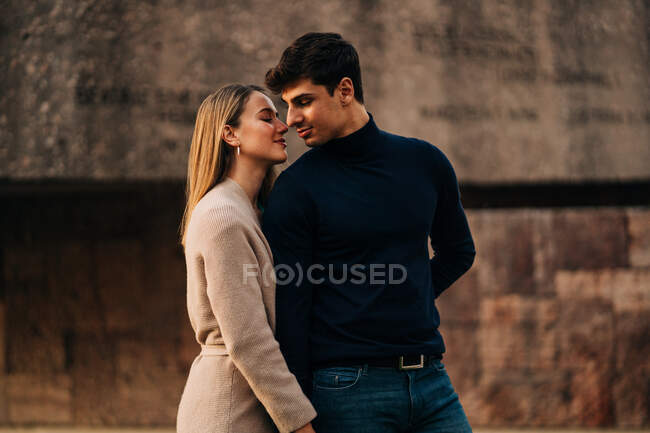 Молода стильна пара стоїть близько один до одного на міській вулиці і посміхається — стокове фото