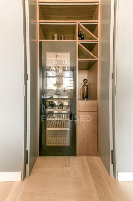 Garrafas de vinho colocadas no refrigerador contemporâneo e em prateleiras de madeira em elegante apartamento projetado em estilo mínimo — Fotografia de Stock