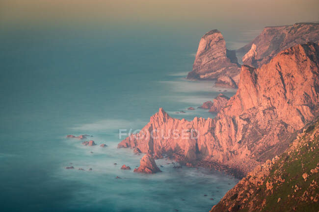 Vista de cima da água do mar salpicando perto de rochas do Cabo Roca localizado no Parque Natural de Sintra Cascais ao nascer do sol em Portugal — Fotografia de Stock
