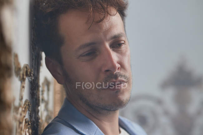 Стрессовый мужчина в костюме, стоящий со скрещенными руками и опирающийся на стену в шикарной комнате — стоковое фото