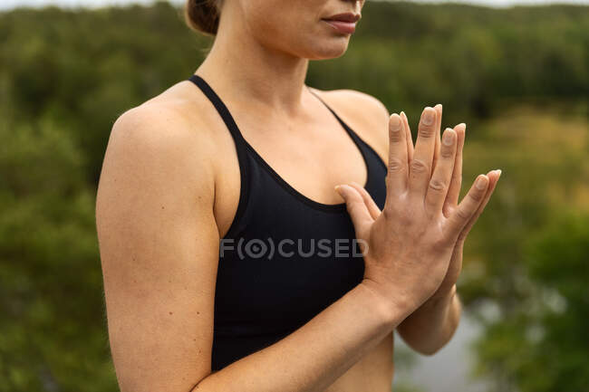 Анонимная молодая внимательная женщина в спортивной одежде медитирует, практикуя йогу на природе — стоковое фото