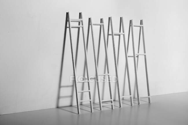 Black and white of ladders against smooth wall with shadow in light room during improvement process at home — Stock Photo
