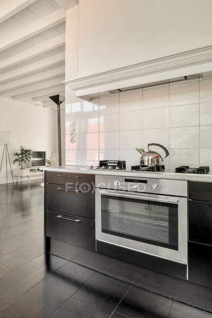 Фрагмент інтер'єру сучасної відкритої кухні з вбудованою піччю і білою плиткою в просторій квартирі в стилі лофт — стокове фото