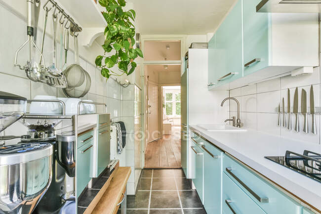 Interior da cozinha contemporânea com mobiliário turquesa e porta aberta para varanda no dia ensolarado de verão — Fotografia de Stock