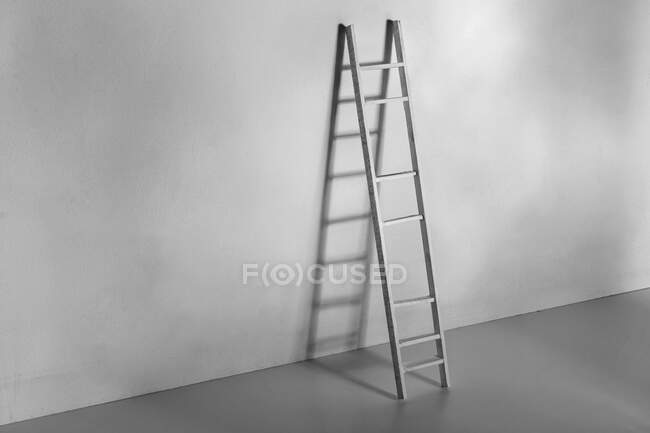 Чорно-біла драбина проти гладкої стіни з тіні в світлій кімнаті під час процесу благоустрою вдома — стокове фото