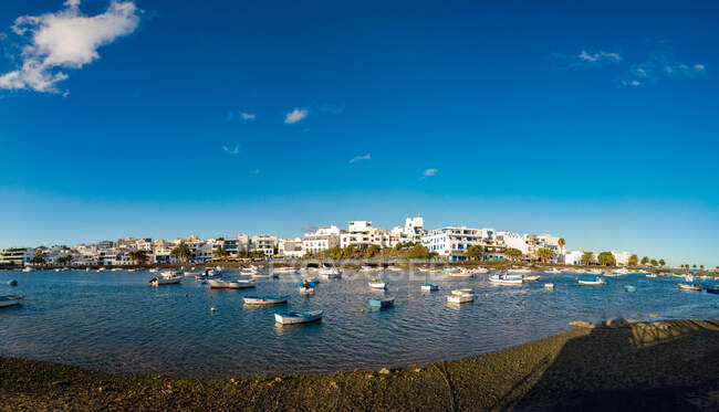 Vista dell'occhio di pesce di molte barche che galleggiano sull'acqua del fiume increspatura vicino alla città contro il cielo blu nuvoloso a Fuerteventura, Spagna — Foto stock
