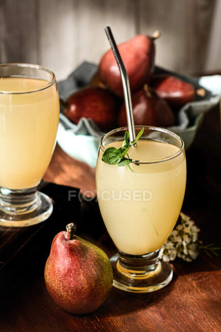 Glasses of delicious refreshing drinks with pear juice and fresh elderflower leaves on table — Stock Photo