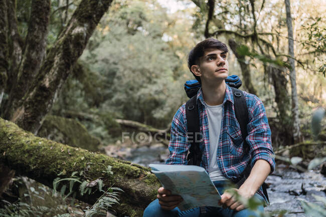 Окаменевший мужчина читает карту во время поиска тропы во время похода в лес — стоковое фото