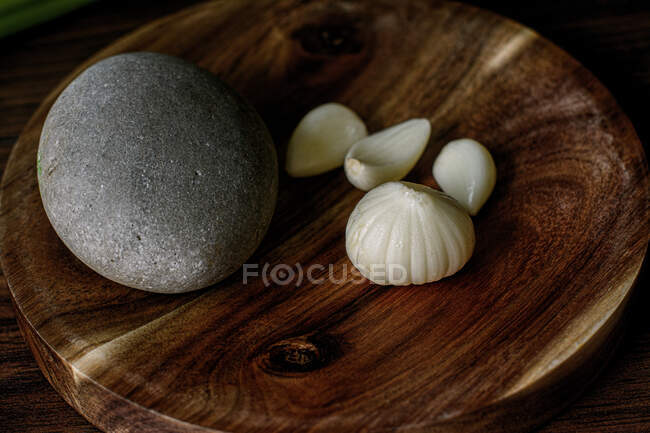 From above of ripe garlic head and cloves placed on wooden mortar with stone on table in kitchen — Stock Photo