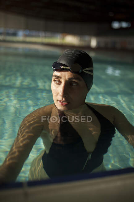 Jovem mulher bonita na piscina interior, vestindo maiô preto — Fotografia de Stock