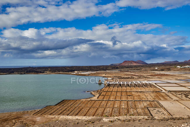 Drone vista dei campi agricoli asciutti situati sulla costa del mare calmo contro cielo blu nuvoloso in estate a Fuerteventura, Spagna — Foto stock