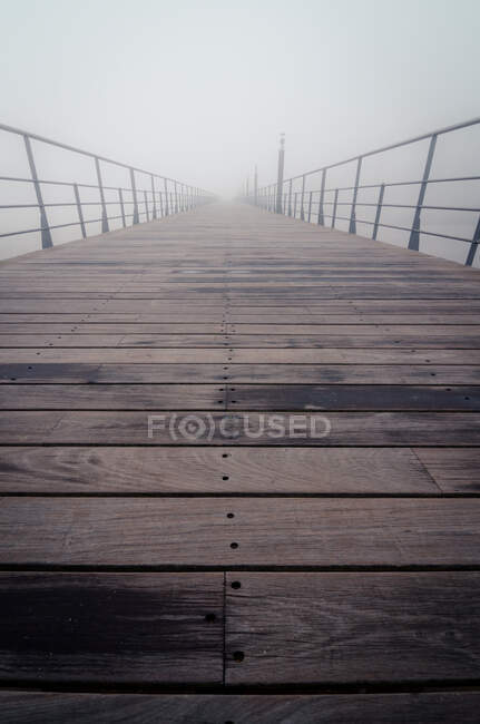Banchina in legno con ringhiere metalliche situata sulla riva del fiume Tago in mattinata nebbiosa a Lisbona, Portogallo — Foto stock