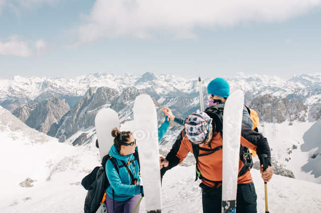 Deportistas con esquís y mochilas que interactúan en la montaña nevada del Pico Aunamend de los Pirineos en Navarra España - foto de stock