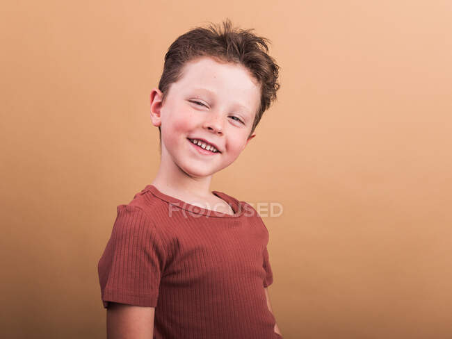 Satisfied child in casual clothes with brown hair looking at camera with toothy smile and tilted head — Stock Photo