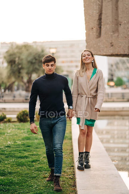 Couple élégant amoureux se tenant la main et marchant en ville tout en profitant du week-end ensemble — Photo de stock