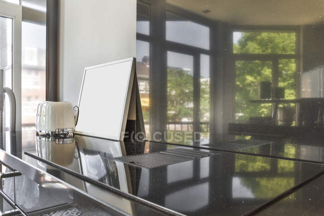 Moderno splashback de vidrio templado para la protección de la pared en la moderna cocina casera con reflejo del interior y las ventanas - foto de stock