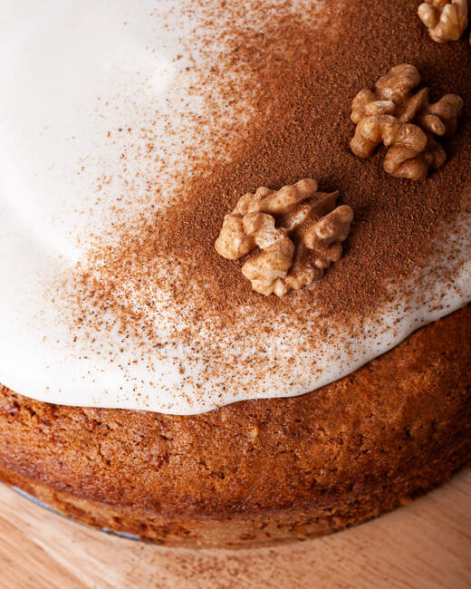 Close-up de saboroso bolo de cenoura com noz e canela em pó em gelo esmalte de açúcar no fundo claro — Fotografia de Stock