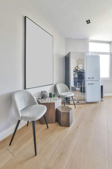 Design de interiores estilo minimalista de apartamento moderno com cadeiras macias e objetos decorativos colocados perto da parede branca com imagem em branco mockup — Fotografia de Stock