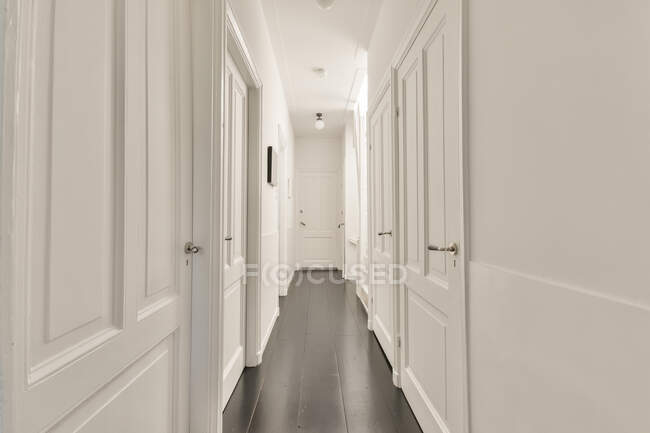 Вид на порожній вузький коридор з білими дверима і стінами в сучасній квартирі — стокове фото