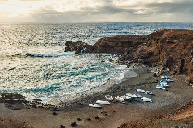 Многие суда, расположенные на побережье штормового моря у скалы в пасмурное утро на Фуэртевентуре, Испания — стоковое фото