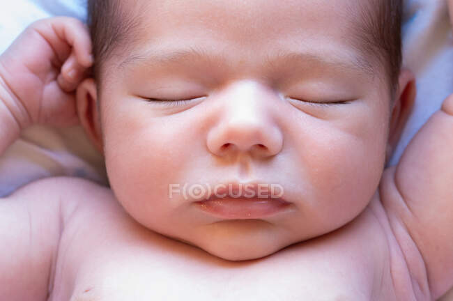 Вид сверху симпатичного маленького обожаемого обнаженного младенца, спящего на мягкой кровати дома — стоковое фото