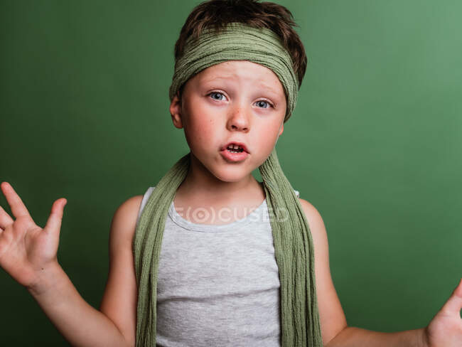 Alegre preteen karatê menino em hachimaki lenço de cabeça de pé no fundo verde no estúdio e se divertindo — Fotografia de Stock