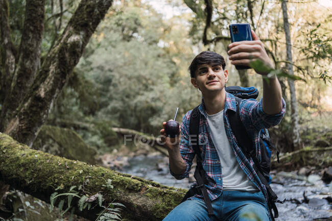 Zufriedener männlicher Wanderer mit Rucksack macht unterwegs Selfie mit Kumpel — Stockfoto