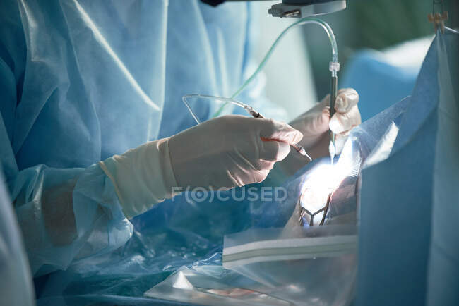 Crop unrecognizable doctor in uniform with syringe injecting medicine into body of patient during surgery in hospital — Stock Photo