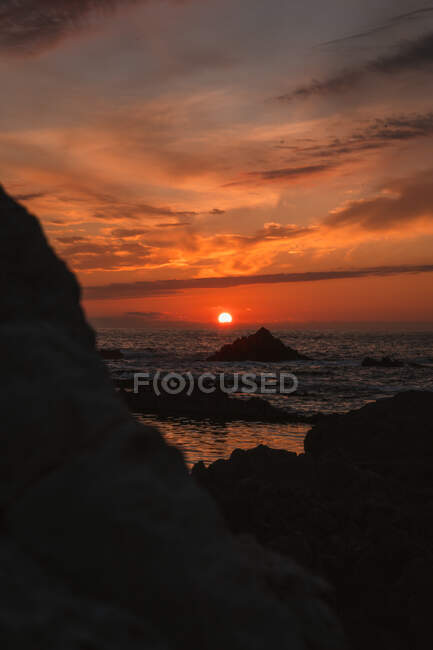 Incroyable paysage paisible de coucher de soleil sur la mer ondulée ondulée avec des roches sous un ciel nuageux coloré en soirée d'été à Liencres Cantabrie Espagne — Photo de stock
