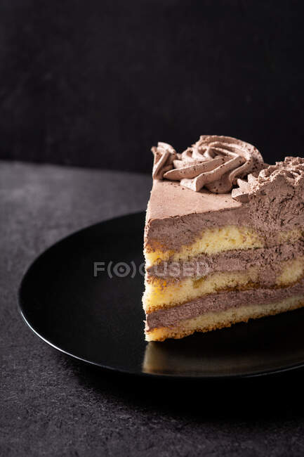 Зверху шматок смачного трюфельного шоколадного торта, який подають у тарілці на чорному столі — стокове фото