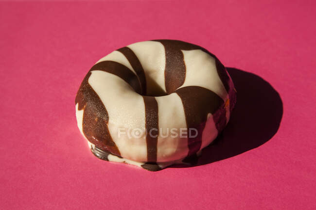 Rosquillas blancas recubiertas de chocolate oreo piezas de galletas sobre fondo rosa - foto de stock