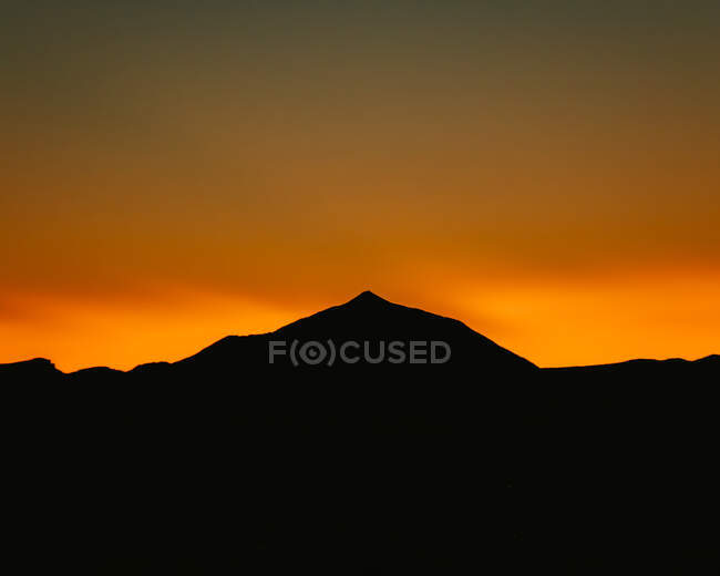 Impresionante paisaje de silueta de cordillera sobre fondo de brillante cielo anaranjado al atardecer - foto de stock