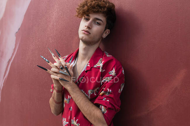 Trendy giovane omosessuale maschio in camicia ornamentale con manicure e mani strette guardando la fotocamera — Foto stock
