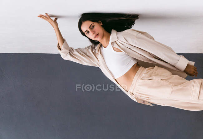 Беззаботная творческая танцовщица, выступающая на городской улице и опирающаяся на стену, демонстрируя загиб и отводя взгляд — стоковое фото